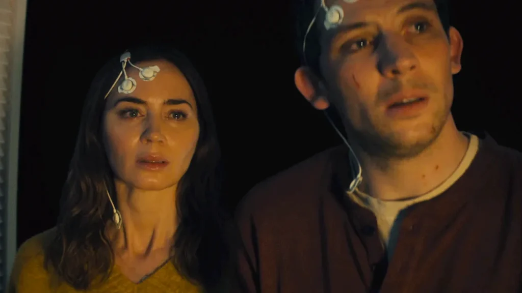 Emily Blunt as Margaret Fairchild and Josh O'Connor as Dr. Daniel Kellner in Disclosure Day, looking shocked with medical sensor wires attached to their foreheads