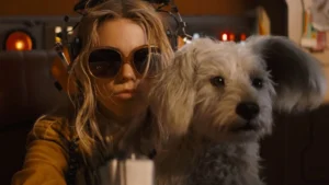 Supergirl hugging her dog Krypto while pouting and wearing sunglasses in the 2026 film