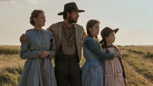 The Ingalls family - Caroline, Charles, Mary, and Laura - standing together in an open, grassy prairie field in a scene from Netflix's Little House on the Prairie.